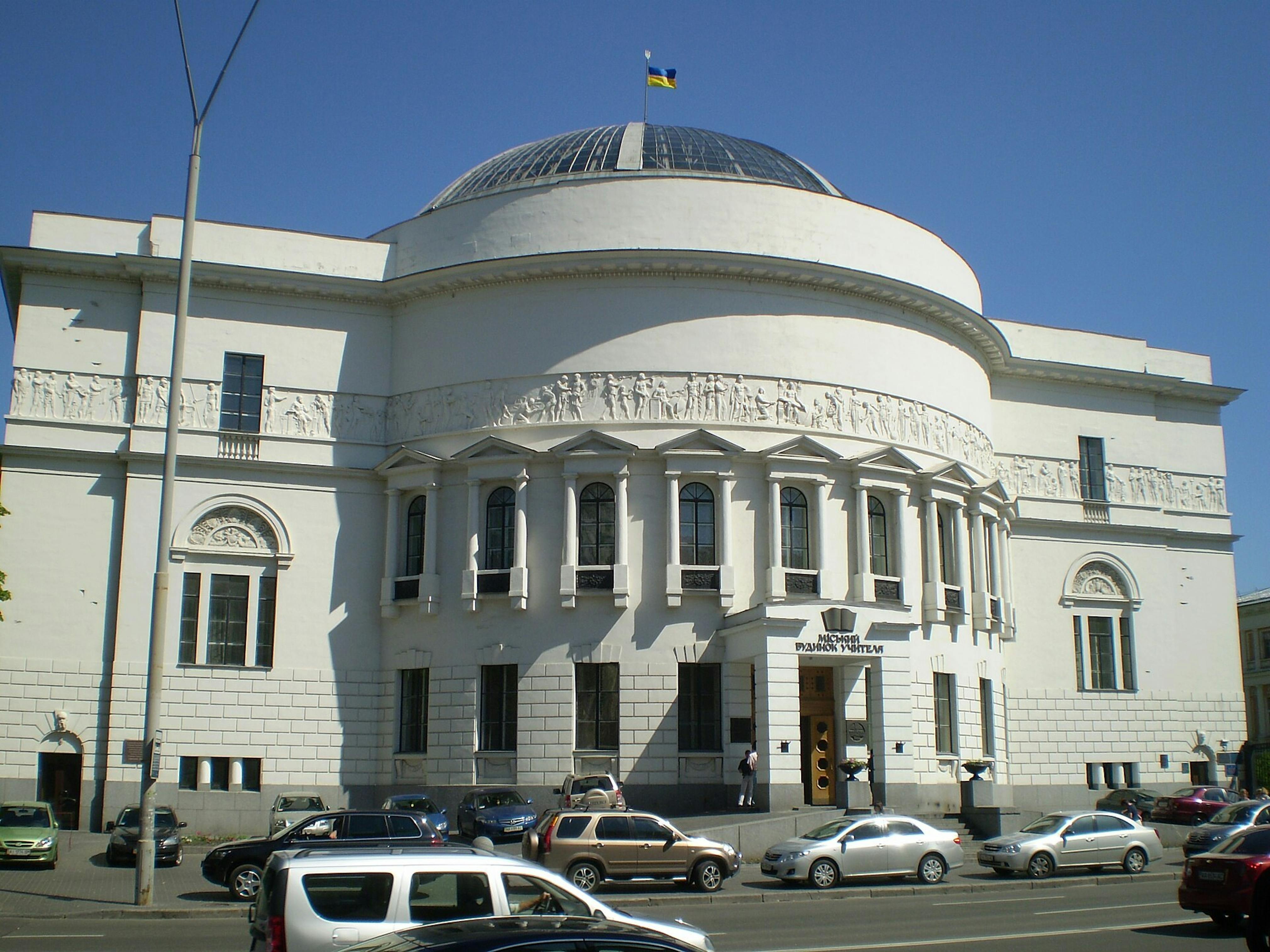 Large white building with glass dome and Ukrainian flag on top