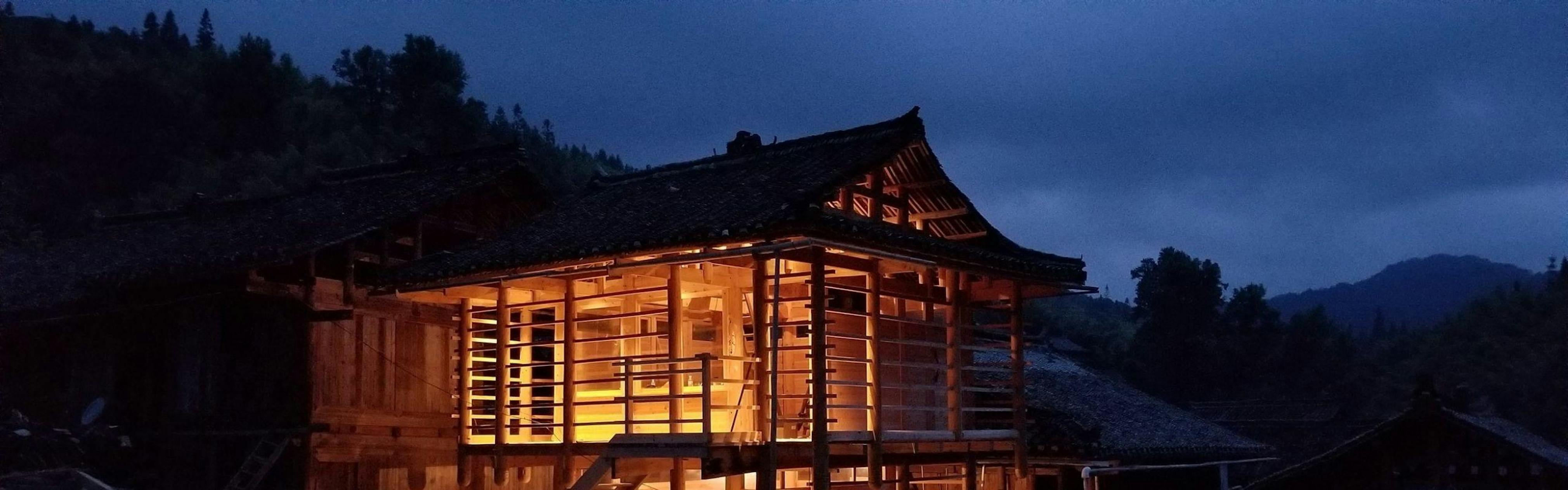 Wooden building with light shining through and night sky in background