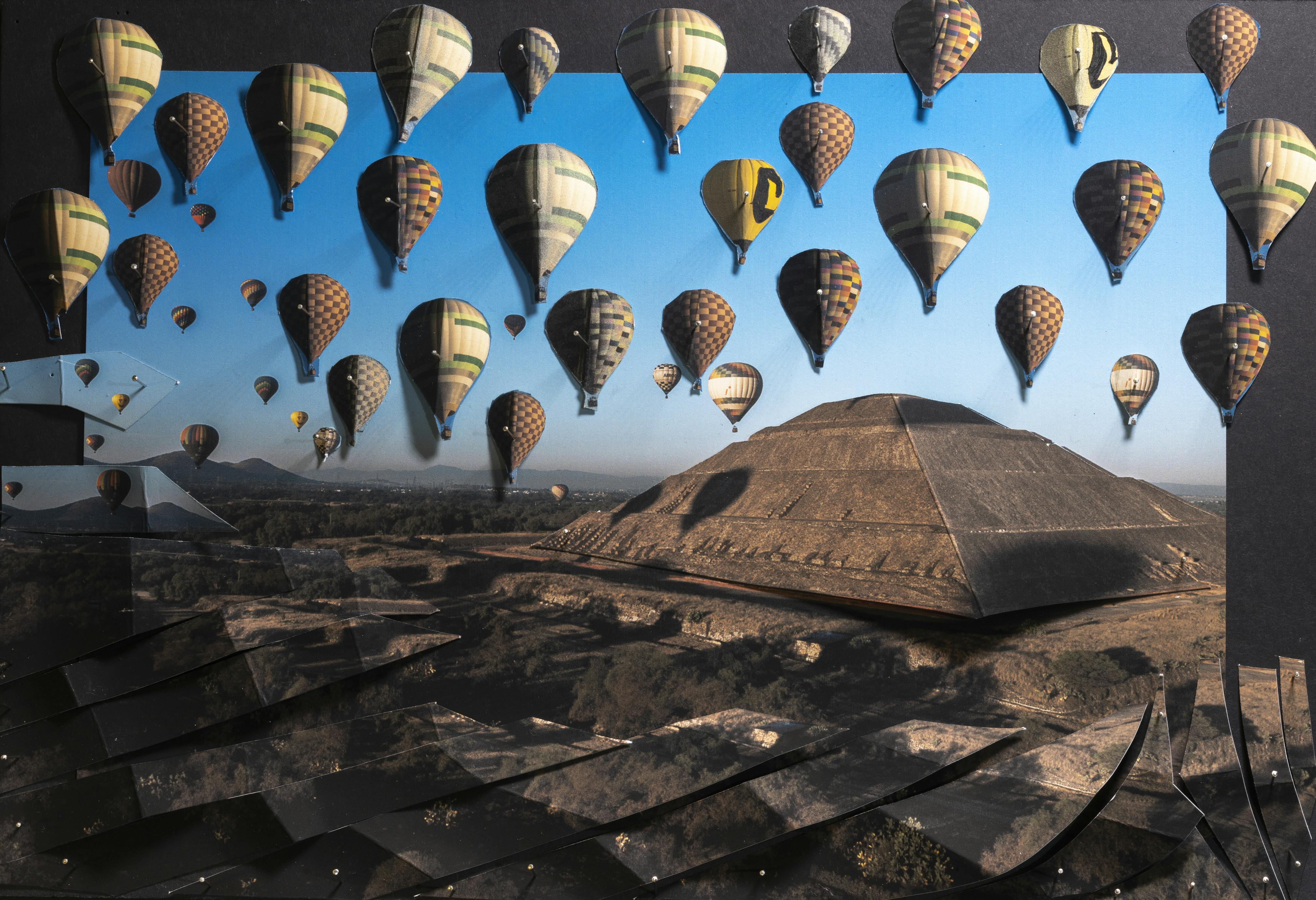 Hot air balloons over an archaeological site. A tall structure stands in the background.